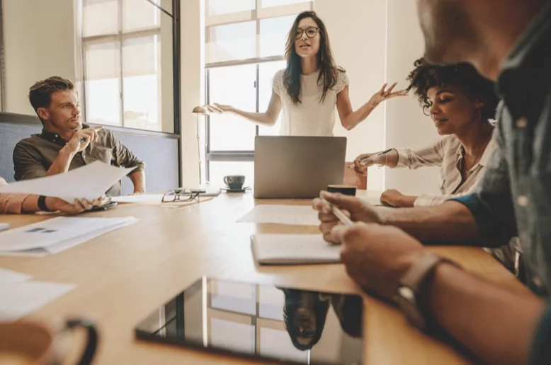 Teammeeting im Startup. Eine Frau spricht animiert, während ihre Kolleg*innen lauschen