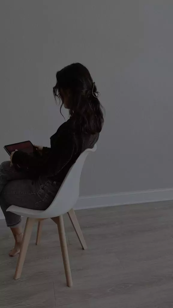 Frau sitzt allein auf einem Stuhl und redet mit einem KI-Chatbot auf ihrem Laptop. Sie hat KI Psychose