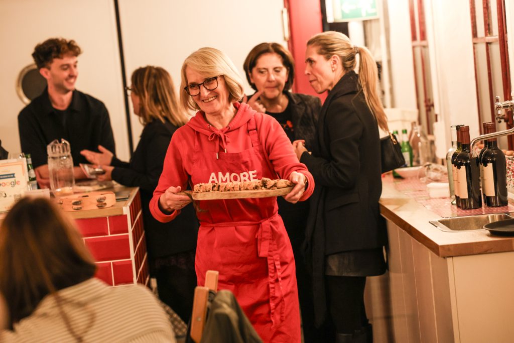 Essen wird serviert auf dem KI Afterwork bei Lettinis, im Hintergrund: Teilnehmerinnen ins Gespräch vertieft